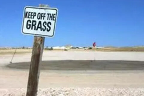 Keep off the grass sign in a dry, barren area.