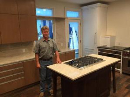 Person standing in a modern kitchen with wooden cabinets and a center island.