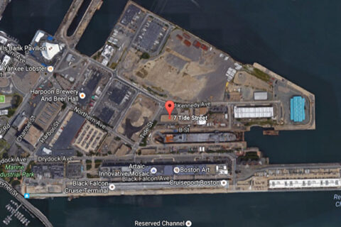 Satellite view of a waterfront industrial area with roads, buildings, and docks.